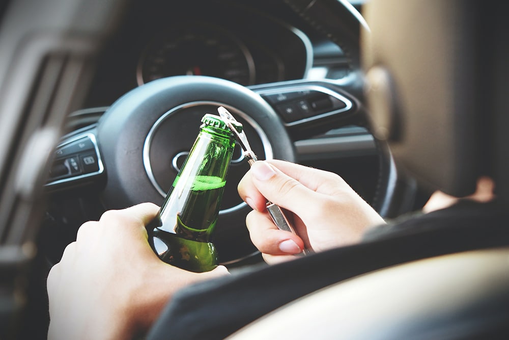 Person behind wheel with beer